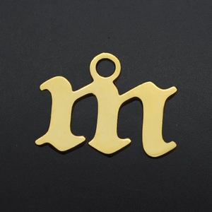 Macro shot of Gothic letter M gold plated stainless steel charm with mirror finish