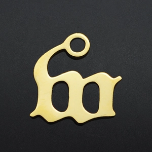 Macro detail of a gothic letter M gold plated stainless steel pendant for necklaces