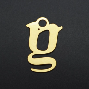 Macro detail of gold lowercase g initial pendant with brushed texture on black background
