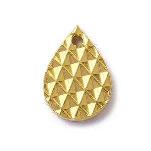Détail macro d'un pendentif goutte doré avec une surface géométrique taillée en diamant