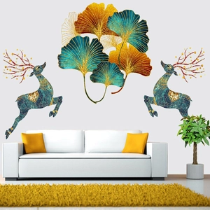 Detail of golden ginkgo leaves and teal deer wall decals over a modern white sofa