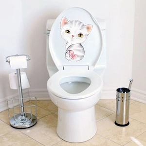 Cute kitten sticker with red bow tie applied on a white toilet seat lid for bathroom deco