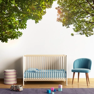 Modern white and wood crib with blue polka dot mattress set under green leaf shadows