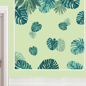 Detail of tropical monstera and palm leaf wall stickers on a green interior wall