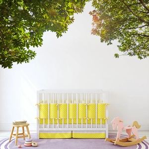 White wooden crib with yellow polka dot bedding set and green tree wall stickers
