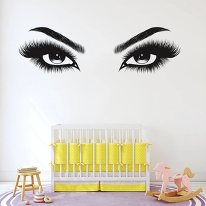 Detail of minimalist vinyl wall sticker showing large eyelashes in a nursery setting