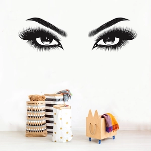 Modern black vinyl wall decal featuring elegant long eyelashes and eyes on a white wall
