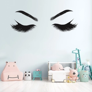 Minimalist black vinyl eyelash wall decal applied to a light blue wall in a cozy bedroom decor