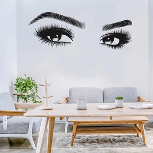 Black vinyl wall decal featuring artistic female eyes and eyelashes in a modern living room