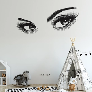 Detail of black vinyl wall sticker showing eyes and lashes in a cozy nursery setting
