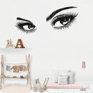 Close-up of black vinyl wall stickers featuring stylish eyelashes in a cozy bedroom setting