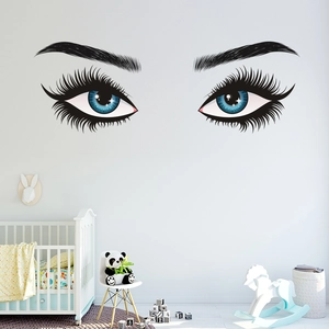 Detailed wall decal of long-lashed blue eyes on a nursery wall with toys and crib