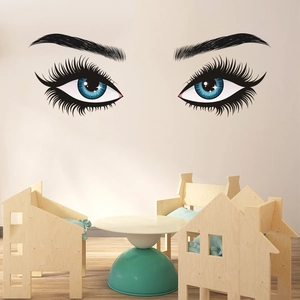 Detail view of large eye wall decals with long lashes and blue pupils on a beige wall