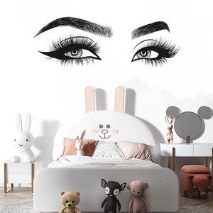 Chic black vinyl eyelashes and eyebrows wall decal applied above a cozy bedroom bed