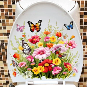 Détail de stickers autocollants fleurs et papillons colorés sur un abattant de WC blanc
