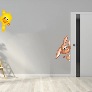 Detailed view of yellow duck and peek-a-boo rabbit stickers on a grey wall and white door