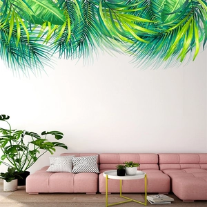 Detail of tropical green palm leaf wall sticker above a pink sofa in a modern living room