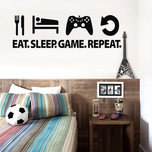 Close-up of black 'EAT SLEEP GAME REPEAT' wall decal in a modern bedroom setting