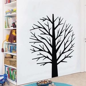 Detail of a black vinyl tree wall sticker applied in a cozy children room with white shelves