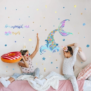 Nursery wall scene showing kids playing near mermaid tail decals and starfish stickers