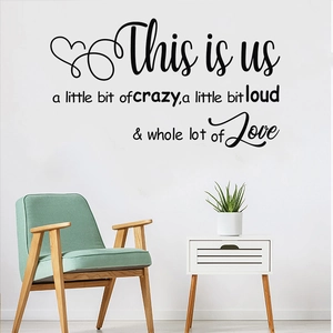 Black This Is Us vinyl wall decal quote with heart accents on a white living room wall