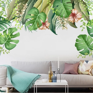 Detail of tropical monstera and hibiscus wall stickers above a grey sofa for home decor