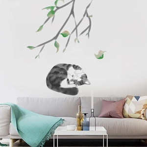 Detail of warm illustration wall sticker featuring a curled cat on a leafy branch decor