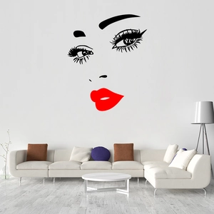 Modern wall sticker with bold red lips and eyelashes above a white sofa in a living room