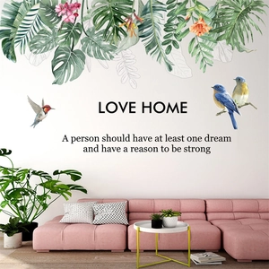 Detail of tropical leaves and birds wall sticker with Love Home quote in a living room
