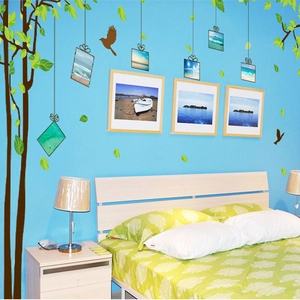 Detailed view of dark brown tree wall decal with green leaves and photo frames on blue wall