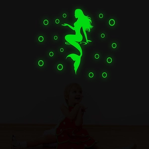 Glow-in-the-dark mermaid and bubbles wall decal shown in a dark room with a child