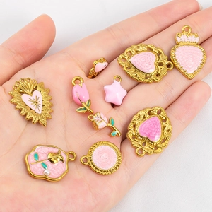 Pendentifs cœur et tulipe en émail rose et acier inoxydable doré tenus en main