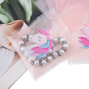 Sacchetto regalo rosa con unicorno contenente un braccialetto di perle bianche e strass