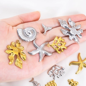 Golden and silver 304 stainless steel sea life charms held in hand for DIY jewelry making