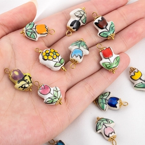 Bunte Keramik-Tulpenanhänger mit Goldring für DIY-Schmuck in der Hand gehalten