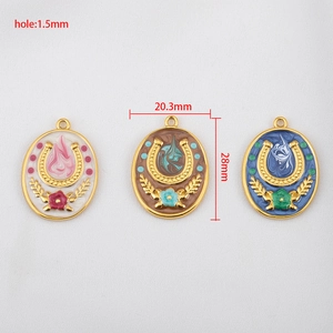 Three colorful enamel horseshoe pendants in white, tan, and blue with gold wheat details
