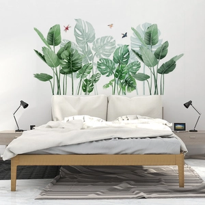 Tropical green leaves wall sticker showing monstera and palm leaves in a bedroom setting