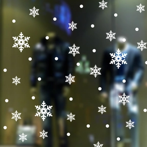 Detailed view of white snowflake window clings applied on a glass storefront surface