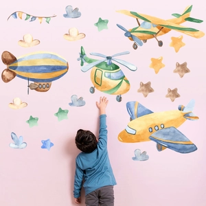 Boy touching watercolor airplane wall stickers with stars and clouds for kids' rooms