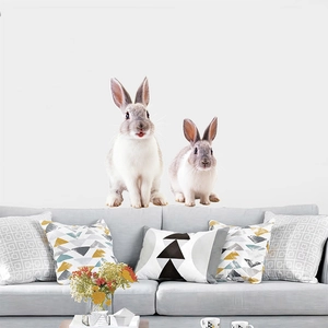 Detail of realistic white and grey rabbit wall stickers applied above a modern living room sofa