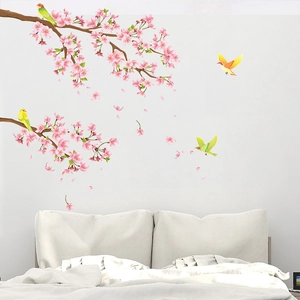 Sticker mural avec fleurs de cerisier roses et oiseaux au-dessus d'un lit moderne