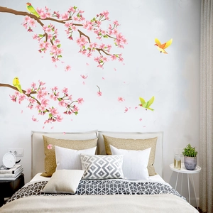 Détail de stickers muraux avec fleurs de cerisier roses et oiseaux colorés sur un mur de chambre