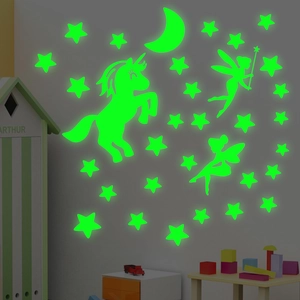 Luminous unicorn and fairy wall stickers glowing green in a dark children's bedroom setup