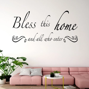 Detail of Bless this home wall sticker on white wall above a modern pink sofa with plants