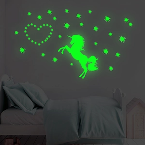 Glow-in-the-dark unicorn wall sticker with heart and stars glowing in a dark bedroom