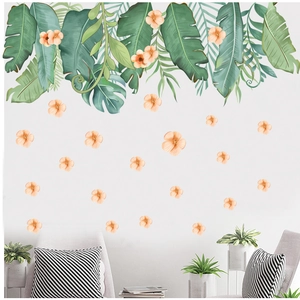 Détail des stickers muraux feuilles tropicales et fleurs roses sur un mur de salon gris