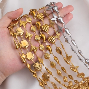 Hand holding layered gold and silver stainless steel charm bracelets with butterfly charms
