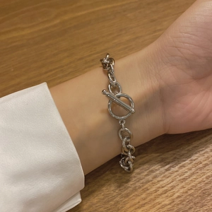 Silver stainless steel chain bracelet with toggle clasp on wrist with wooden background