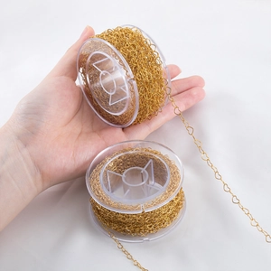 Detail of golden heart-shaped metal link chain wrapped on a transparent plastic spool