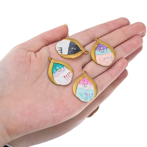 Handheld view of colorful teardrop shell pendants with gradient enamel and pearls